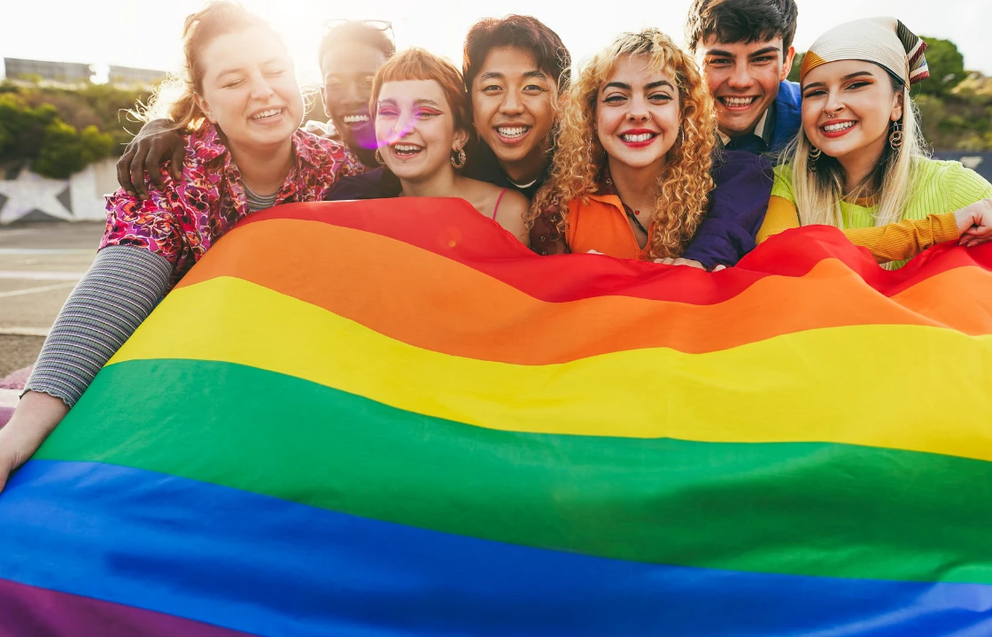 Regenbogenflagge gehalten von lachenden Menschen